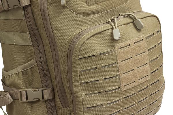Close-up of a beige Elite Survival Systems PULSE 24-Hour Backpack featuring MOLLE webbing and a velcro patch area, with focus on the zippers and buckle.