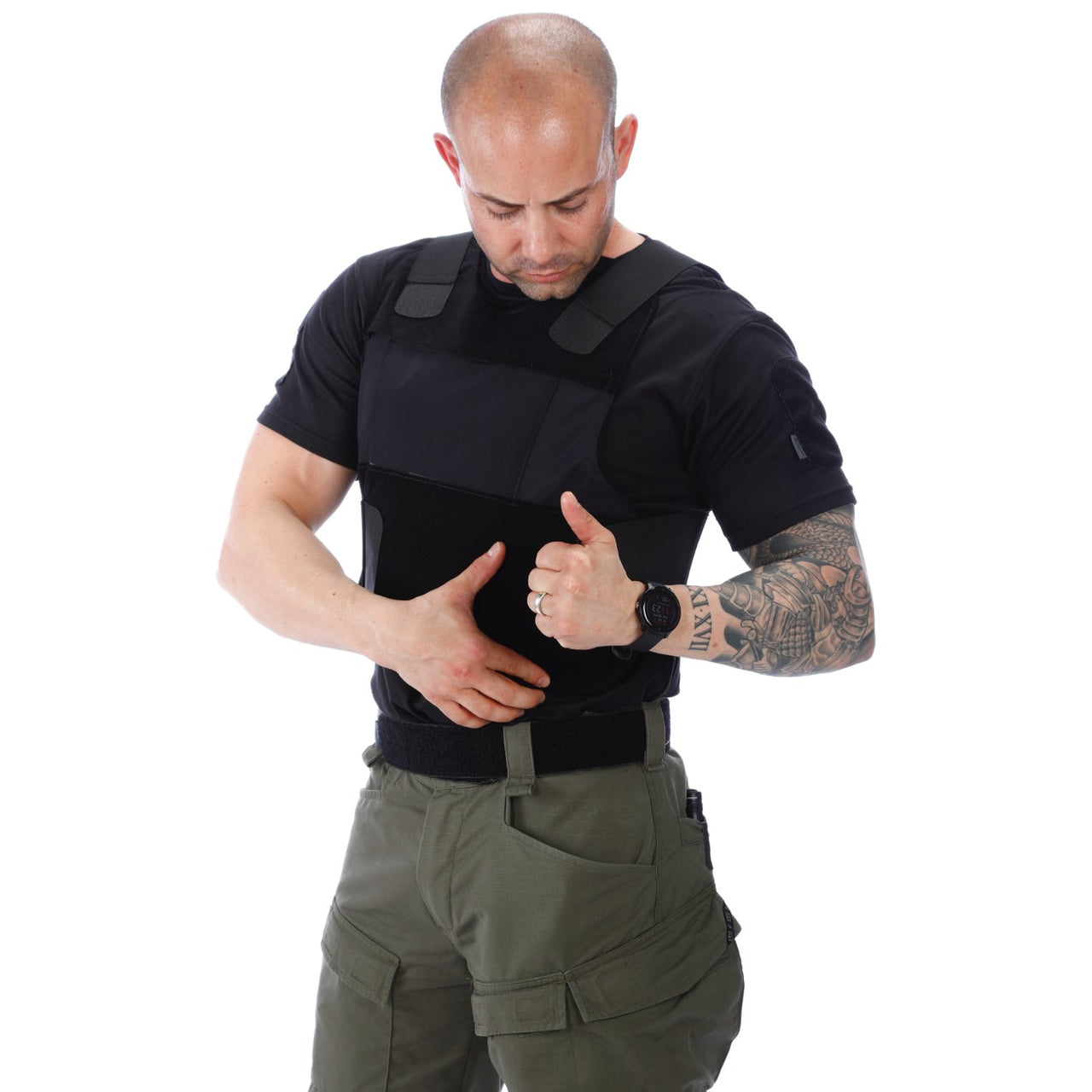 A man wearing a black t - shirt and green pants was spotted wearing the Body Armor Direct All American Concealable Enhanced Multi-Threat Vest, manufactured by Body Armor Direct.