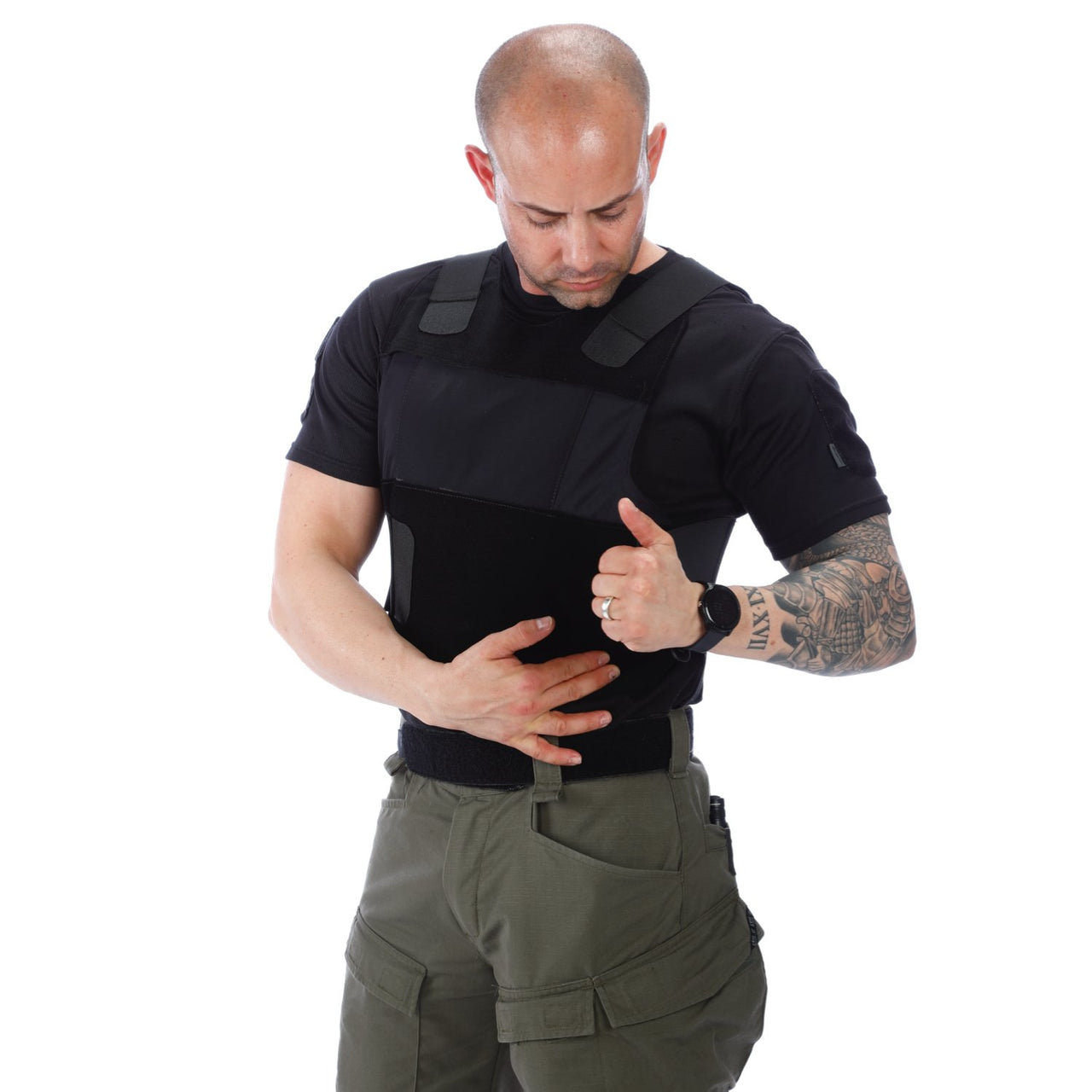 A man wearing a black shirt and green pants, carrying the Body Armor Direct All American Concealable Enhanced Multi-Threat Vest from Body Armor Direct.