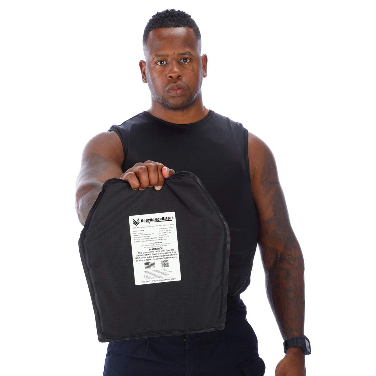 A man with tattoos holding a Body Armor Direct VIP T-Shirt Concealable Enhanced Multi-Threat plastic bag.