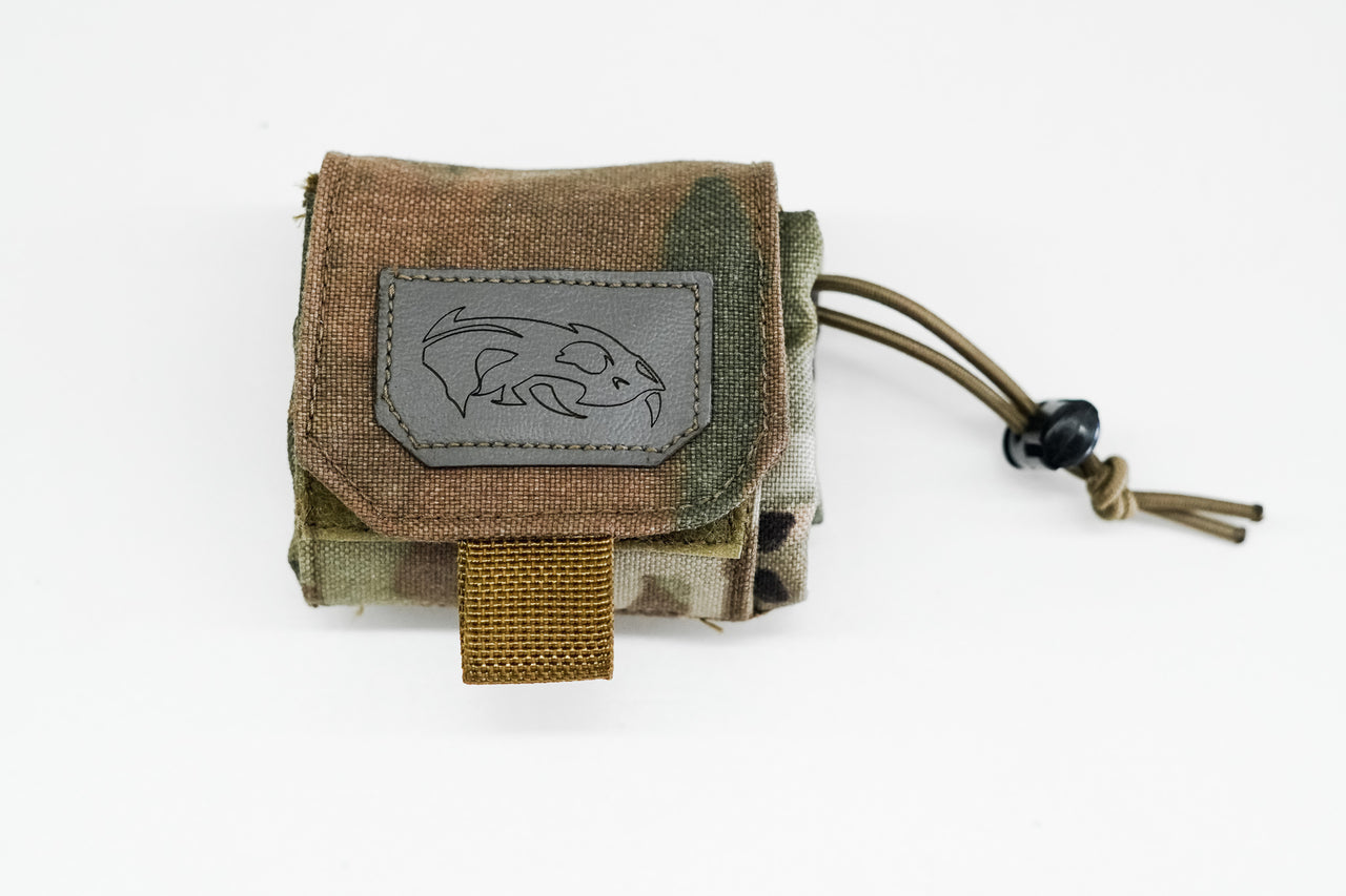A small camouflaged Predator Armor Dump Pouch with a dolphin emblem on a patch, secured with a black drawstring, isolated on a white background.