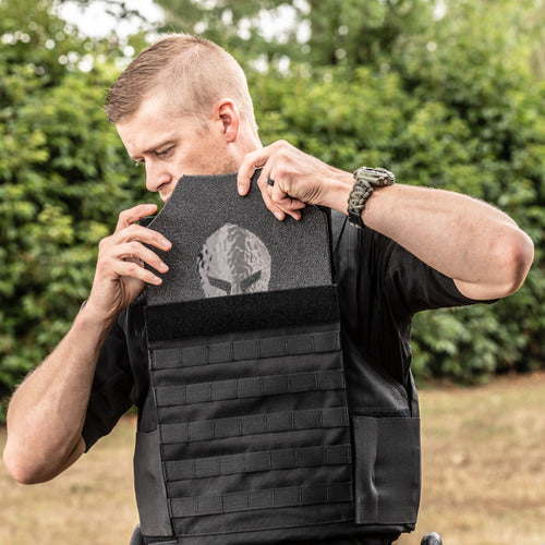 A man is holding a Spartan Armor Systems Tactical Level IIIA Certified Wraparound Vest in front of a tree.