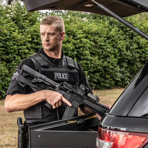 A police officer holding a Spartan Armor Systems Tactical Level IIIA Certified Wraparound Vest in the trunk of a car.