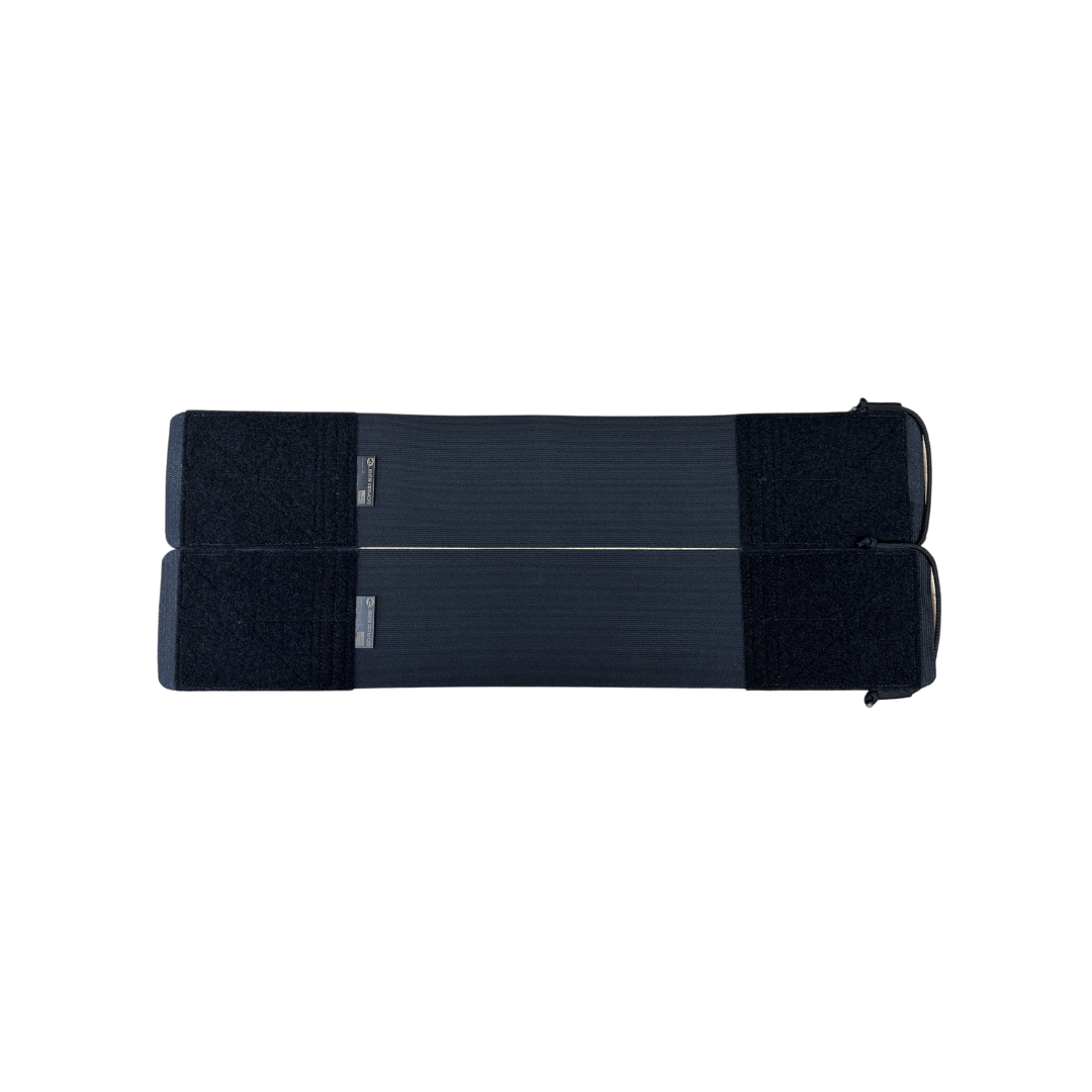 Two black rectangular fabric straps, the Caliber Armor DV8 Replacement Cummerbund by Caliber Armor, designed for armor plate carriers with hook-and-loop fasteners, are laid flat and parallel on a plain white background.