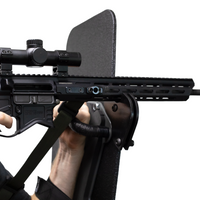 Thumbnail for Close-up of a rifle with a scope resting on a support bracket that is mounted to a bulletproof shield