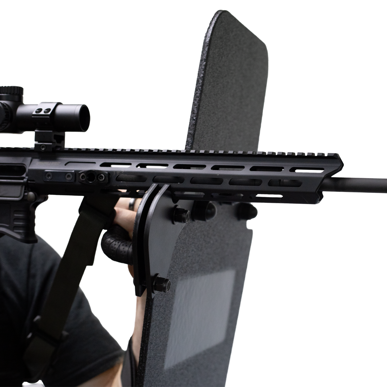 Close-up of a rifle being supported by a ballistic shield that has a ambidextrious weapon support bracket attached