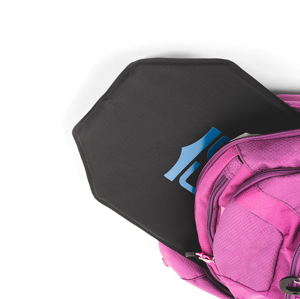 A Caliber Armor CaliberX IIIA Soft Body Armor Panel is partially inserted into the open compartment of a pink backpack, displayed on a white background.