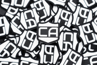 Thumbnail for A stack of black and white Caliber PVC Morale Patches by Caliber Armor features bold 