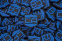 Thumbnail for A stack of Caliber Armor's blue and black Caliber PVC Morale Patches, shaped like Guardian Shields and featuring 