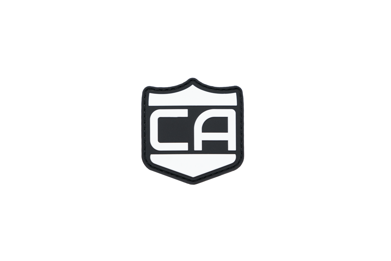 The Caliber Armor Caliber PVC Morale Patch is a black and white shield-shaped patch with bold "CA" lettering in the center, inspired by a classic Guardian Shield—an ideal addition to your tactical gear collection.