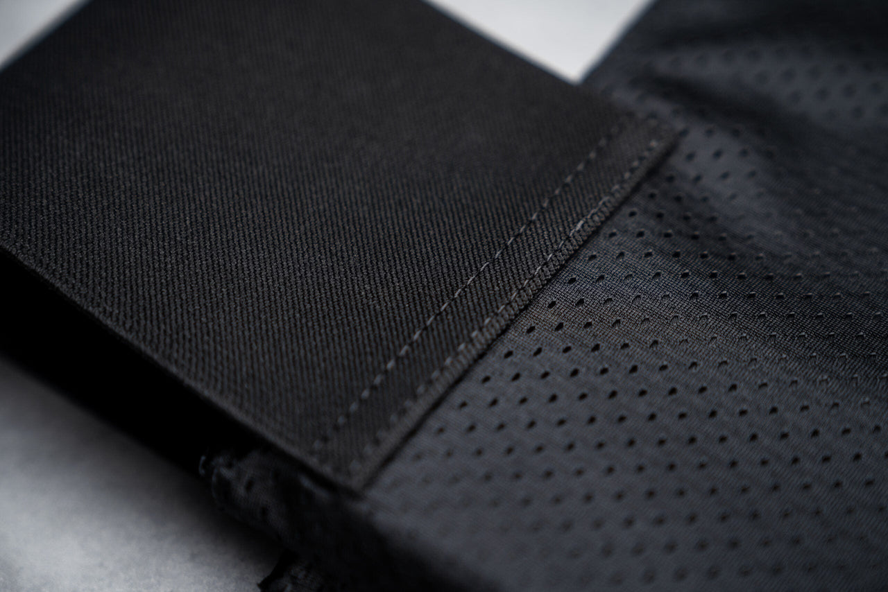 Close-up of black, textured, and perforated fabric with visible stitching detail from the Caliber Armor CaliberX IIIA Gray Man Concealable Package, designed for discreet soft armor panel carry.