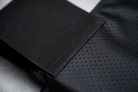 Thumbnail for Close-up of the Gray Man Concealable Carrier by Caliber Armor shows black, perforated fabric with a stitched seam beside non-perforated fabric—designed for discreet carry and compatible with soft armor panels.