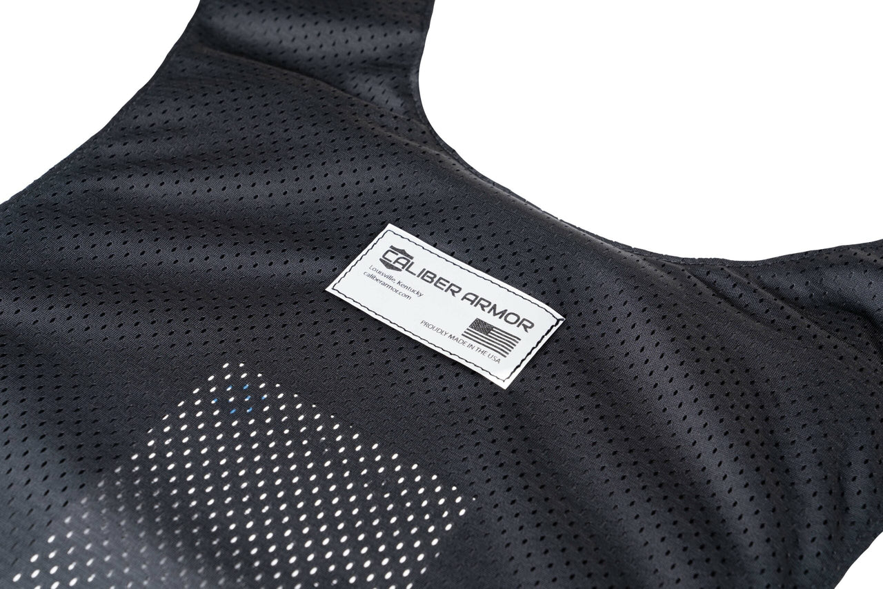 Close-up of a black mesh fabric Caliber Covert Concealable Vest by Caliber Armor, featuring a rectangular label stitched on the front.