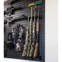 Thumbnail for Black plastic vertical four gun storage mount, both upper & lower portion of mount shown mounted to our black  Assault Wall slat wall paneling loaded with shotguns & muzzelloaders with other tactical gear and guns shown mounted surrounding the mount