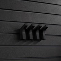Thumbnail for Black AR-15 magazine hanger, installed on an Assault Wall tactical slat wall, close up view showing the hanger without rifle magazines installed or hanging