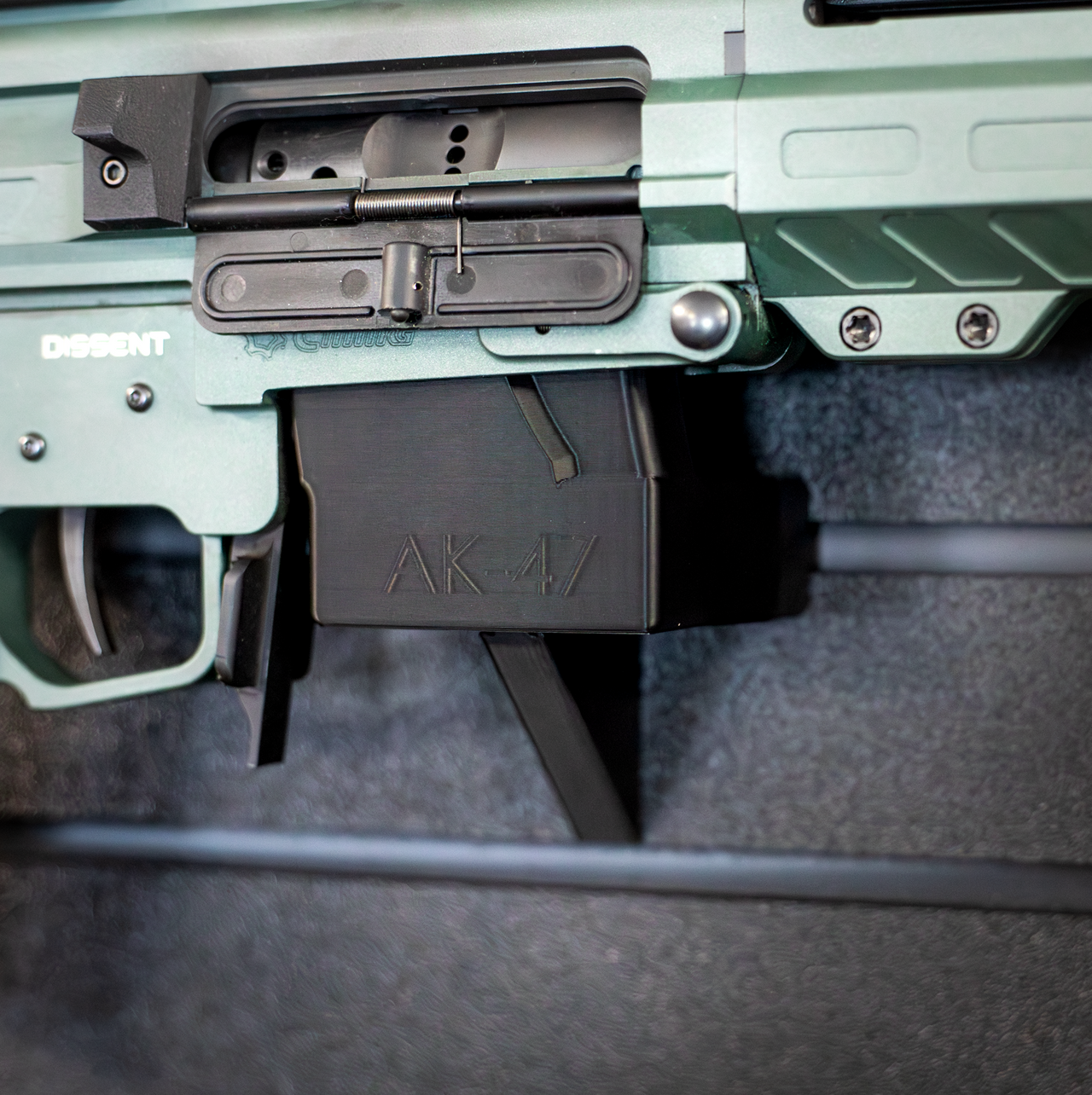 Close-up of an AK-47 rifle mounted by its magazine well on an Assault wall caliber specific gun mount installed on a slat wall