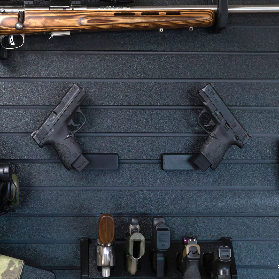Left & Right facing black plastic caliber specific  mag mounted pistol hangers installed on Assault Wall Tactical slat wall showcasing the adjustable mounting angles and directional mounts.