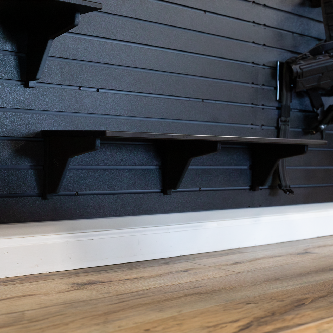 30" black plastic shelf with three shelf support brackets mounted to a black Assault Wall tactical slat wall 