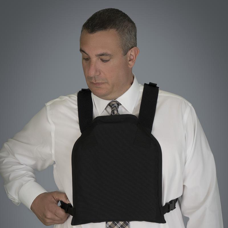 A man in a white shirt and tie adjusting a black Body Armor Direct Active Shooter Defense Kit over his attire.