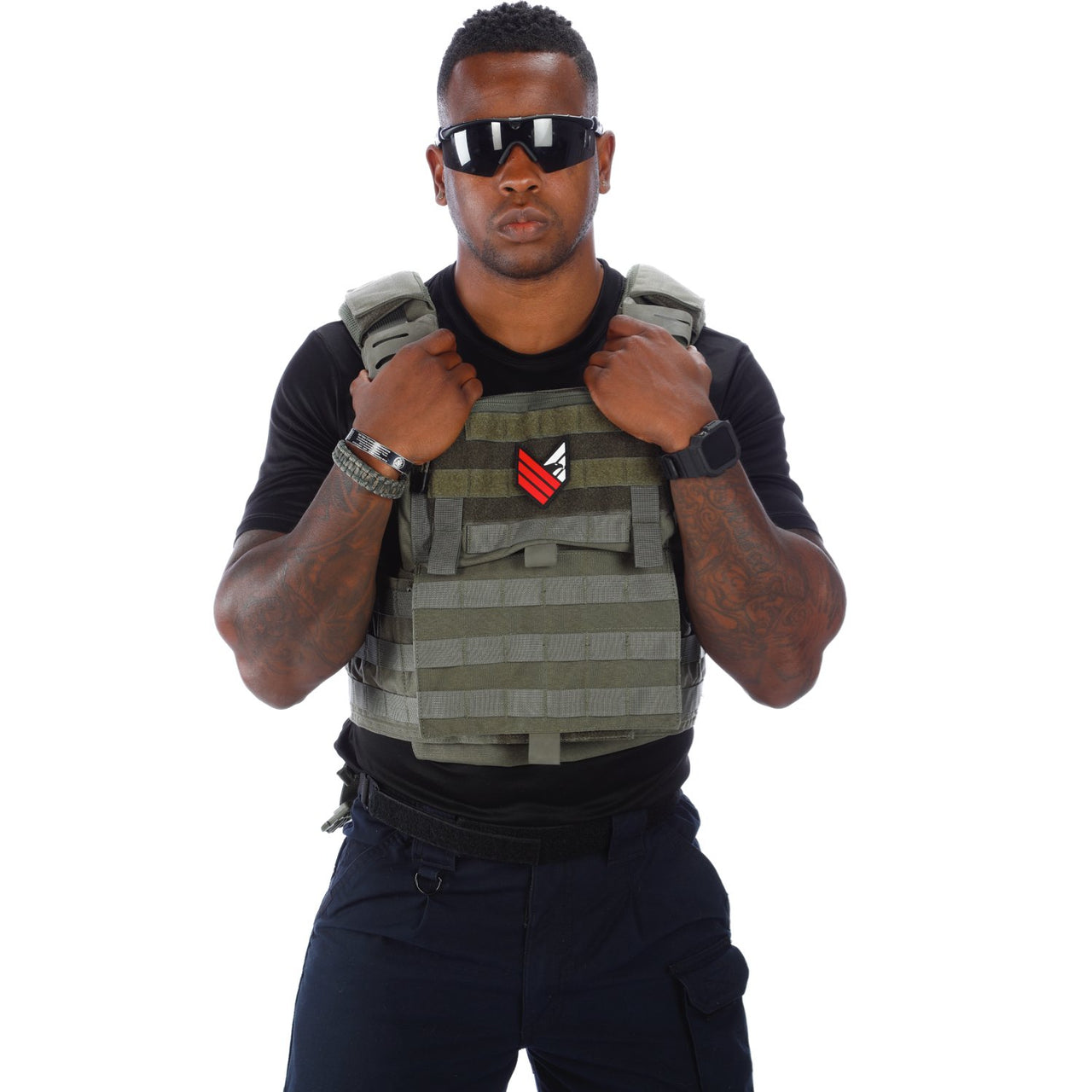 A fit man wearing a Body Armor Direct Victory Plate Carrier Deluxe Edition and sunglasses, adjusting the vest with both hands, isolated on a white background.