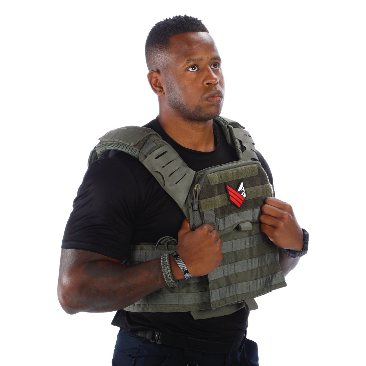 A man adjusting a Body Armor Direct Victory Plate Carrier Deluxe Edition tactical vest, wearing a black t-shirt, looking to the side with a serious expression.