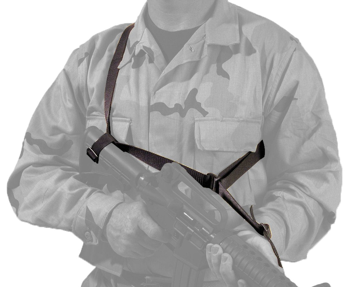 Person in a camouflage military uniform holding a rifle with an Elite Survival Systems Quick-Adapt Tactical Sling, upper body visible, with a gray background.