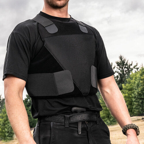 A man in a black shirt standing in a field wearing the Spartan Armor Systems Concealable IIIA Certified Wraparound Vest.